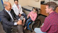 cerebral palsy patient in wheelchair with father and doctors